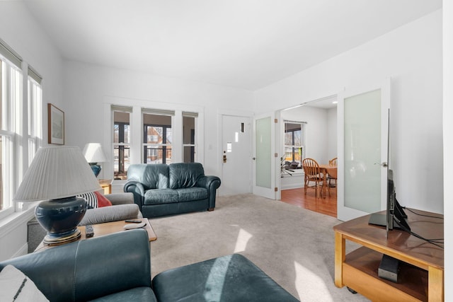 living area with a healthy amount of sunlight, french doors, and carpet