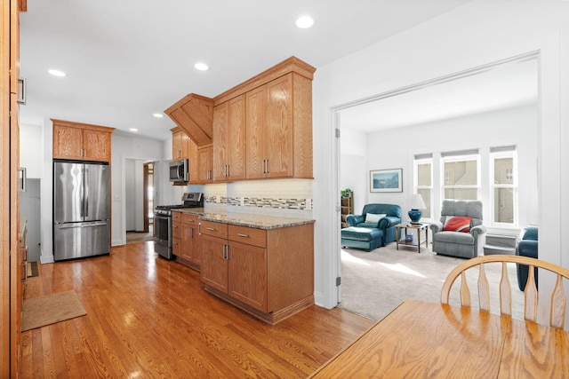 kitchen featuring decorative backsplash, recessed lighting, light wood finished floors, and stainless steel appliances