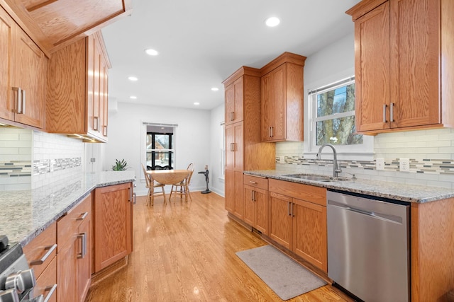 kitchen featuring a sink, stainless steel dishwasher, recessed lighting, light wood finished floors, and light stone countertops