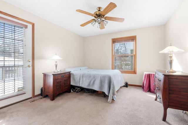 bedroom with multiple windows, light carpet, and baseboards