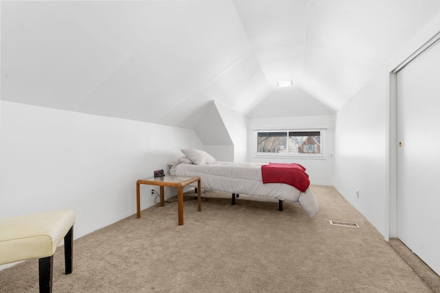 bedroom with visible vents, light colored carpet, and lofted ceiling