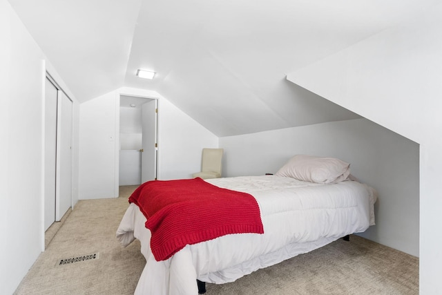 carpeted bedroom featuring visible vents, a closet, and vaulted ceiling