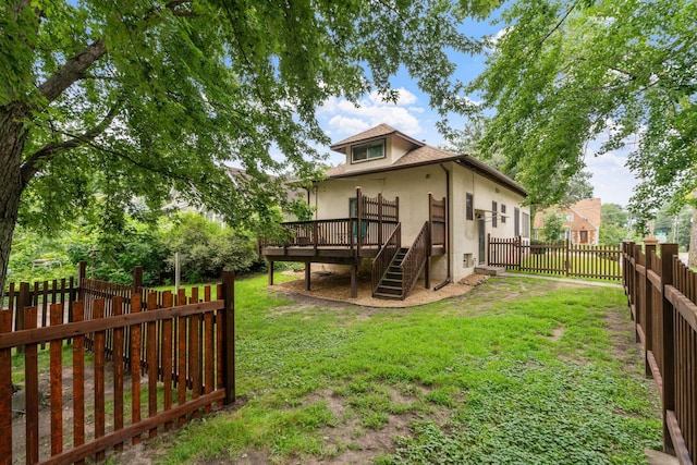 back of house featuring a wooden deck, a yard, a fenced backyard, and stucco siding