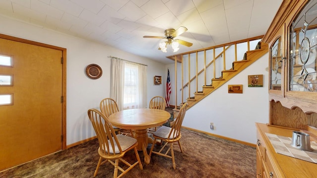 dining room featuring carpet flooring, baseboards, stairs, and ceiling fan