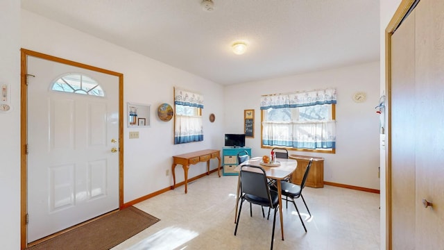 dining space featuring baseboards and light floors