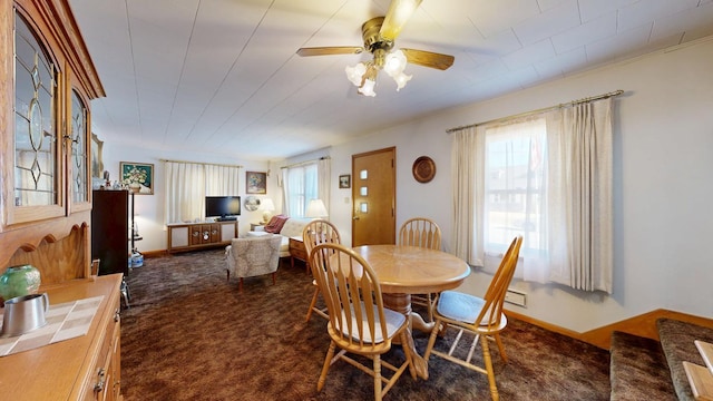 dining room featuring dark carpet, baseboards, and ceiling fan