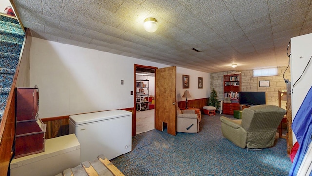 carpeted living room featuring a wainscoted wall and wood walls