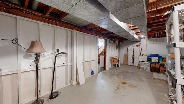 unfinished basement featuring stairs and concrete block wall