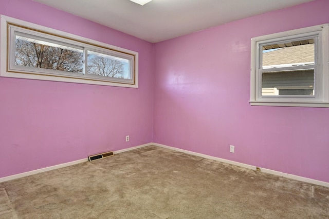 carpeted spare room featuring baseboards and visible vents