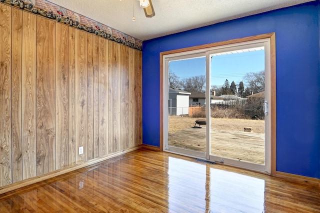 unfurnished room featuring baseboards, a textured ceiling, ceiling fan, and wood finished floors