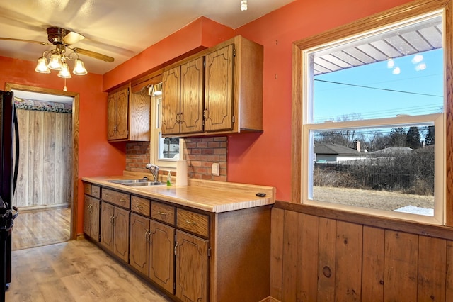 kitchen with brown cabinetry, light wood-type flooring, light countertops, and a sink