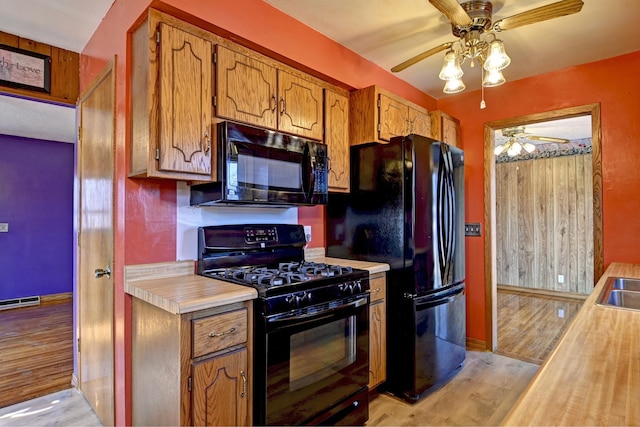 kitchen with brown cabinetry, visible vents, light wood finished floors, black appliances, and light countertops