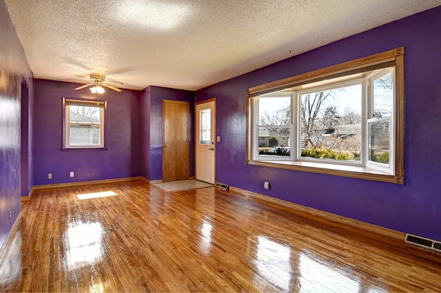 unfurnished room featuring a ceiling fan, baseboards, visible vents, and wood-type flooring