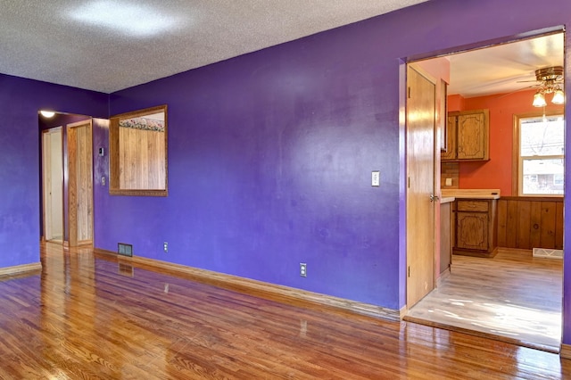 unfurnished room featuring visible vents, a textured ceiling, a ceiling fan, and wood finished floors