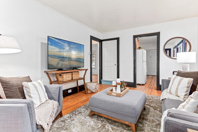 living room featuring light wood-type flooring, baseboards, and crown molding