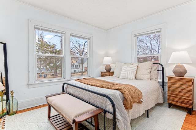 bedroom with baseboards, ornamental molding, and light wood finished floors