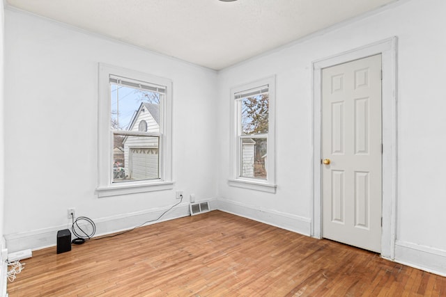 spare room with plenty of natural light, baseboards, visible vents, and hardwood / wood-style floors