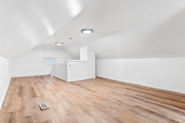 additional living space featuring visible vents, baseboards, wood finished floors, and vaulted ceiling