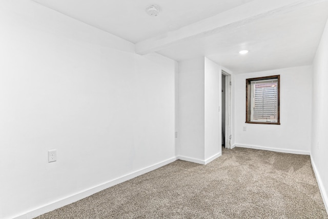 carpeted spare room featuring baseboards and beam ceiling