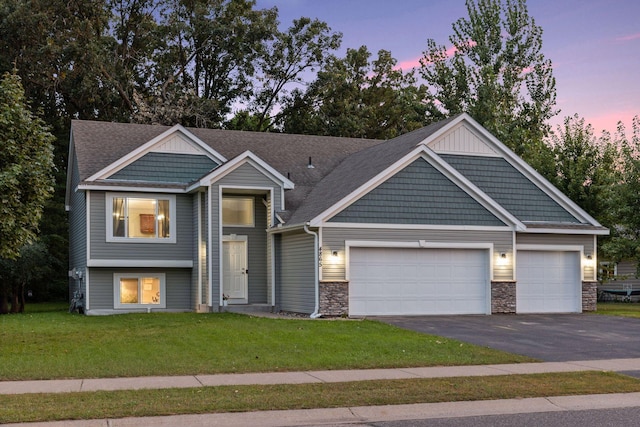 view of front facade with a yard, stone siding, driveway, and a garage