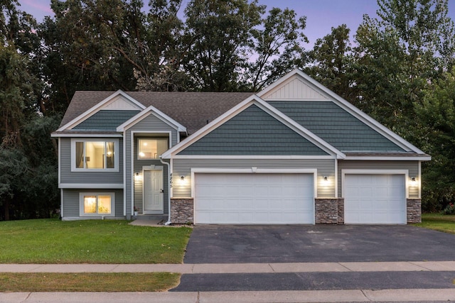 craftsman-style house featuring a yard, stone siding, and driveway