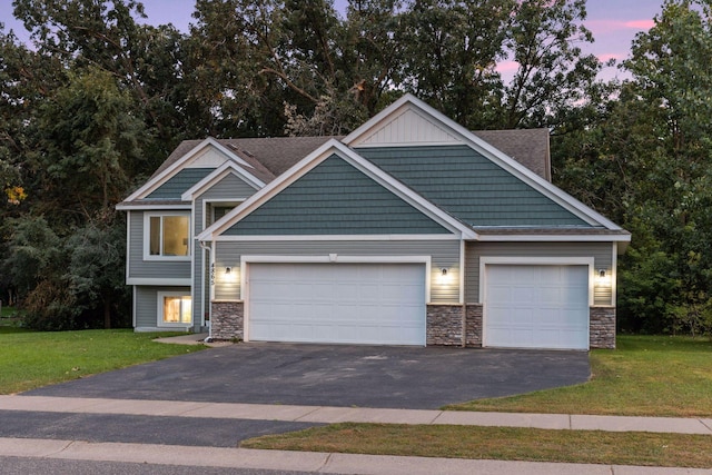 craftsman house featuring an attached garage, a lawn, stone siding, and driveway