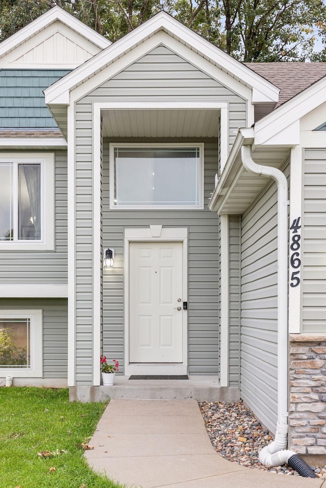 doorway to property with roof with shingles