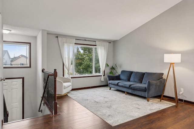 living area featuring baseboards, lofted ceiling, and wood finished floors