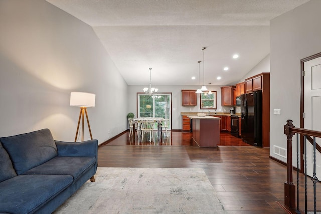 living room with dark wood-style floors, visible vents, an inviting chandelier, and lofted ceiling