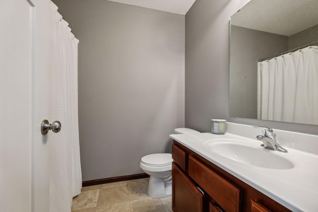 bathroom featuring toilet, a textured ceiling, and vanity