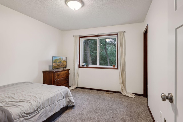 carpeted bedroom featuring baseboards and a textured ceiling