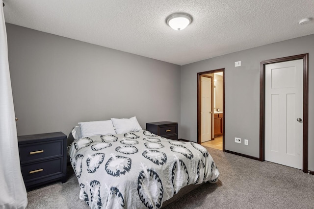 bedroom with ensuite bathroom, baseboards, carpet floors, and a textured ceiling