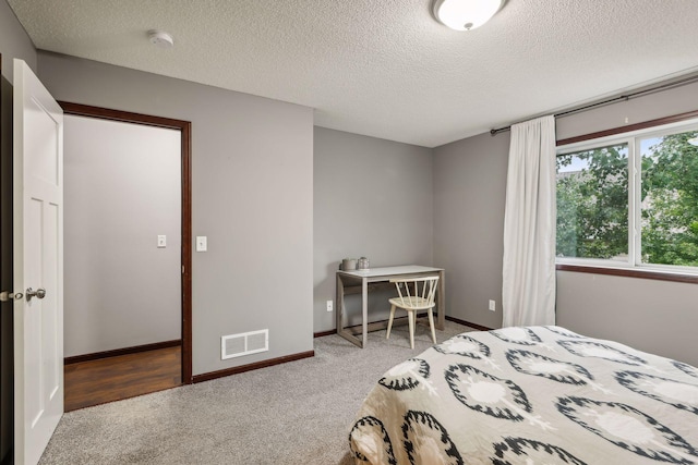 carpeted bedroom featuring visible vents, a textured ceiling, and baseboards