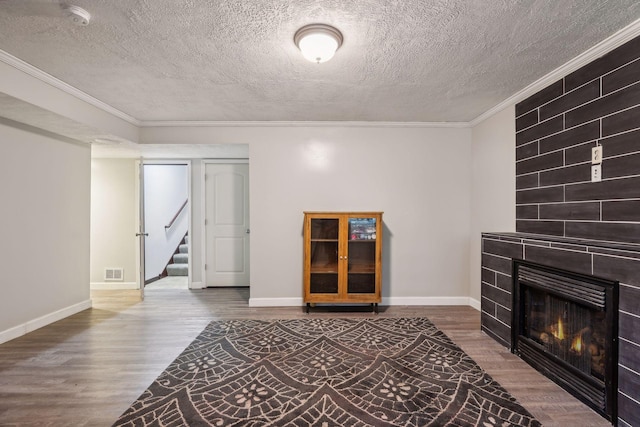 living area featuring wood finished floors, visible vents, a fireplace, ornamental molding, and stairs