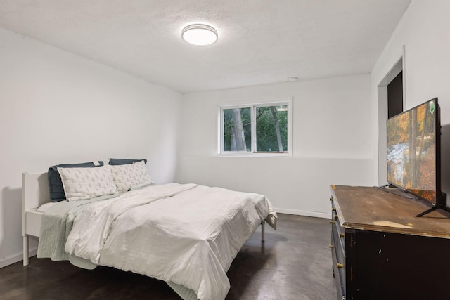 bedroom featuring concrete floors and baseboards