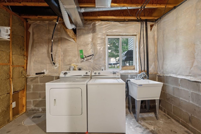 clothes washing area with a sink, independent washer and dryer, and concrete block wall