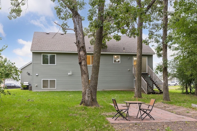 back of property featuring stairs, a patio area, a lawn, and a shingled roof