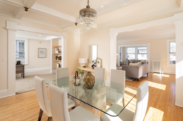 dining area featuring decorative columns, ornamental molding, radiator heating unit, and light wood finished floors