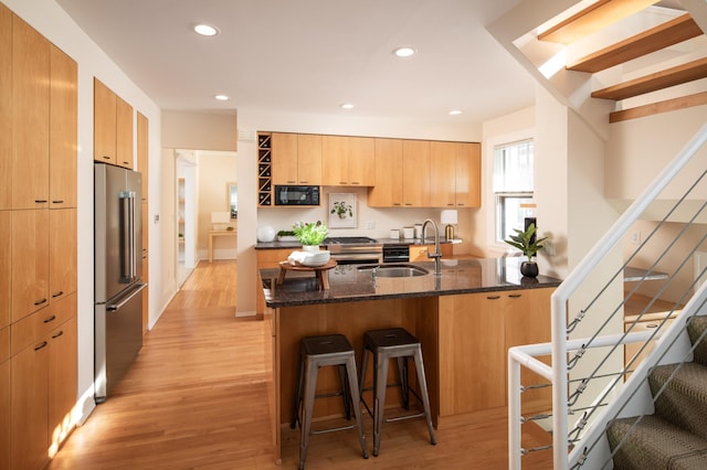 kitchen featuring a breakfast bar, a peninsula, high end fridge, black microwave, and modern cabinets