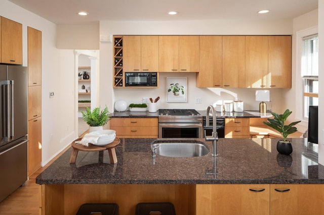 kitchen featuring dark stone counters, recessed lighting, light wood-style floors, and appliances with stainless steel finishes