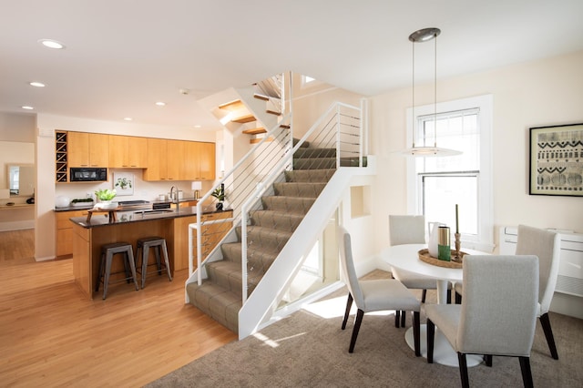 dining room with stairs, light wood-style flooring, and recessed lighting