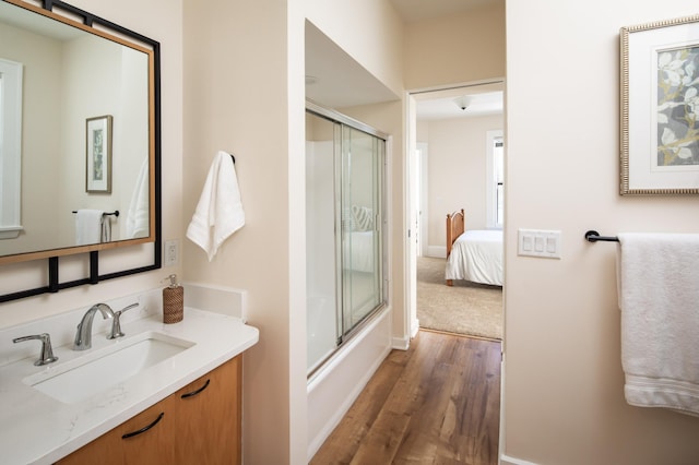 full bathroom featuring vanity, wood finished floors, baseboards, and enclosed tub / shower combo