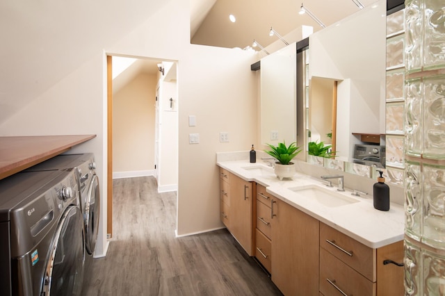 bathroom with baseboards, double vanity, separate washer and dryer, wood finished floors, and a sink