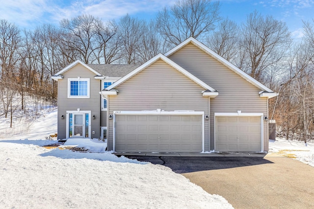 view of snow covered exterior with a garage and driveway