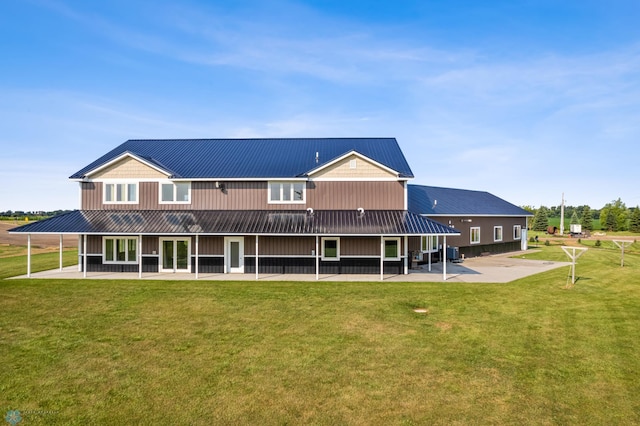 rear view of house with metal roof, a lawn, and a patio area