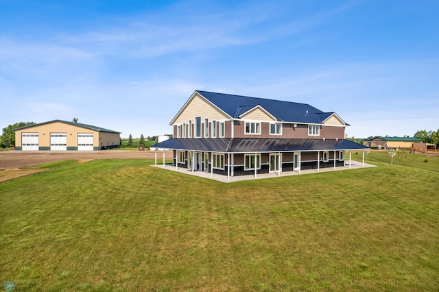 rear view of house featuring driveway, metal roof, a detached garage, and a yard