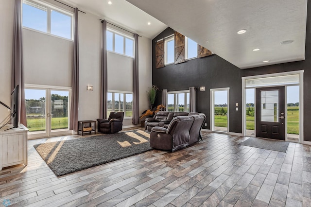 unfurnished living room with recessed lighting, wood finished floors, and a towering ceiling