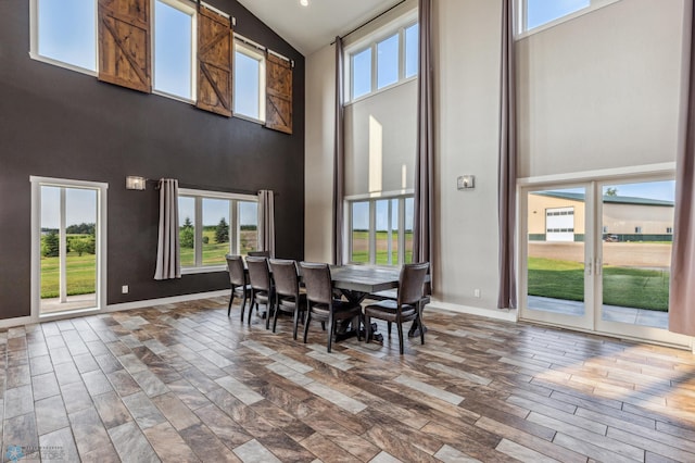 dining room with baseboards, high vaulted ceiling, and wood finished floors