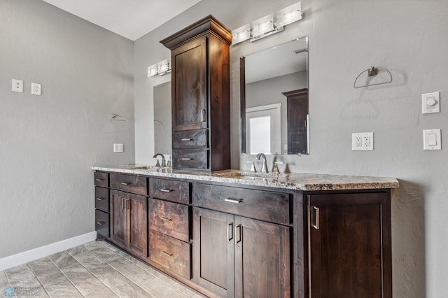 full bath with a sink, baseboards, and double vanity