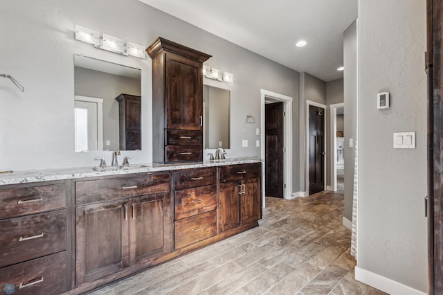 full bathroom with a sink, baseboards, and double vanity